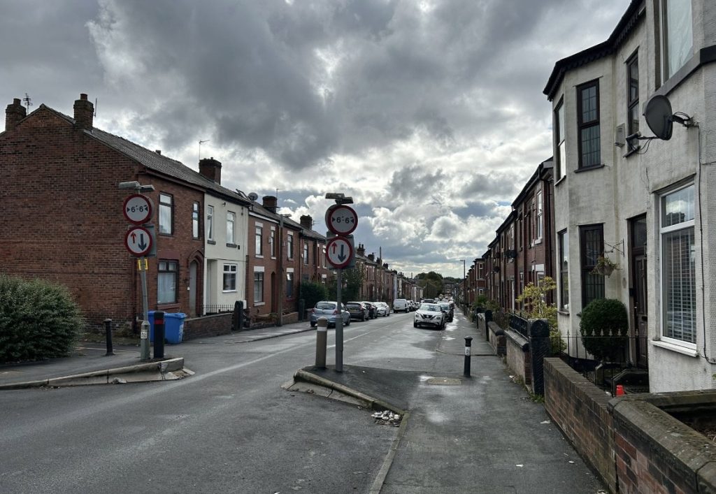 Park Street in Swinton. The street is empty of traffic but there are cars parked up on either side of the street.